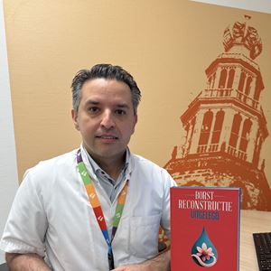 Plastisch chirurg Mahyar Foumani zit in de spreekkamer met zijn boek 'borstreconstructie uitgelegd' Plastisch chirurg Mahyar Foumani zit in de spreekkamer met zijn boek 'borstreconstructie uitgelegd'